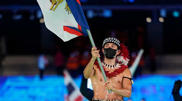Nathan Crumpton, of American Samoa, carries his national flag into the stadium during the opening ceremony of the 2022 Winter Olympics, Friday, Feb. 4, 2022, in Beijing.